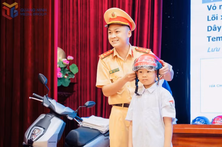 Cán bộ Đội Cảnh sát giao thông đường bộ số 1 (Phòng CSGT, Công an tỉnh) hướng dẫn trẻ em phường Mạo Khê cách đội mũ bảo hiểm đúng quy cách