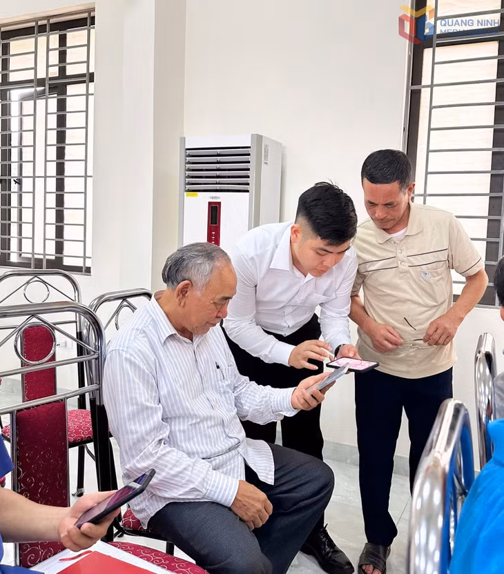 Anh Nguyễn Bá Khải (ở giữa) hướng dẫn người dân trên địa bàn phường cài đặt các ứng dụng trên điện thoại thông minh.