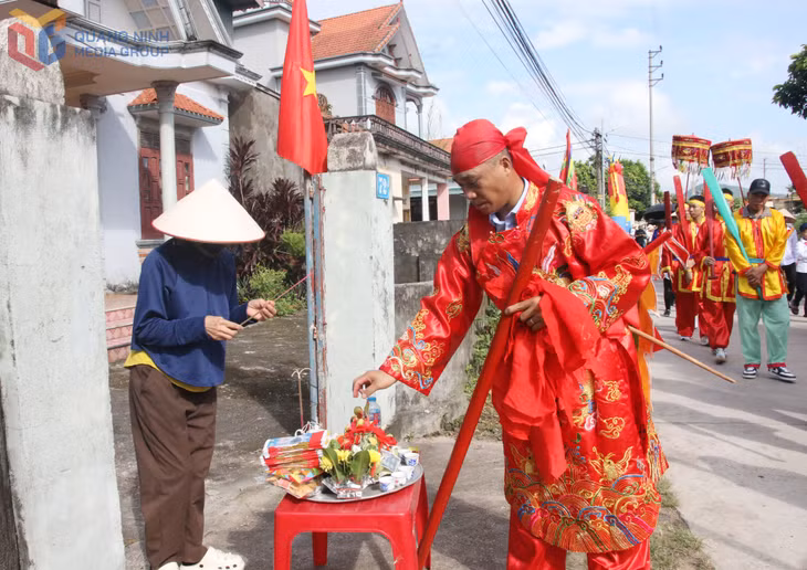 Ngài Vạn Cảnh trong đoàn rước kiệu vừa đi vừa chia lộc cho người dân địa phương.