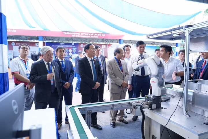 Các đại biểu tham quan gian hàng về một dây chuyền sản xuất sử dụng cánh tay robot tự động tại triển lãm.