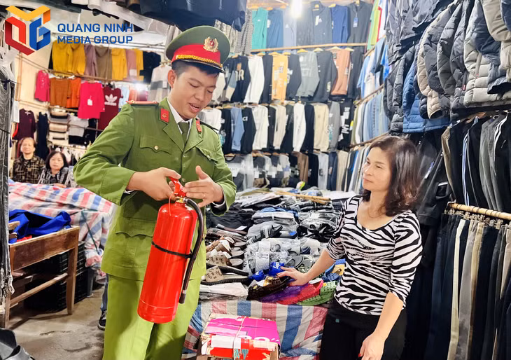 Cán bộ Đội Cảnh sát PCCC&CNCH (Công an TP Cẩm Phả) hướng dẫn tiểu thương sử dụng bình chữa cháy.