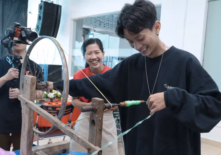 Hào hứng với công đoạn kéo sợi tái chế ni lông để thành chất liệu làm sản phẩm thời trang - Ảnh: LINH ĐINH