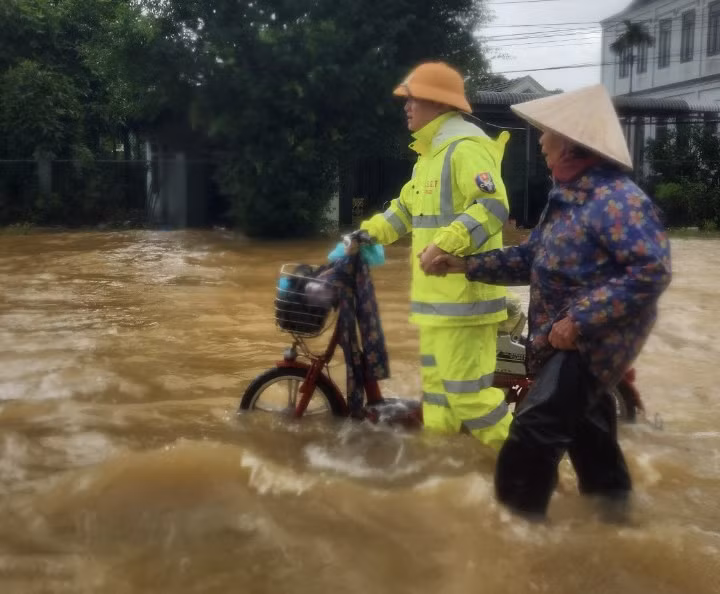 Cán bộ CSGT Công an Thừa Thiên Huế hỗ trợ một cụ già qua đoạn ngập lụt trên QL1A đoạn qua huyện Phú Lộc.