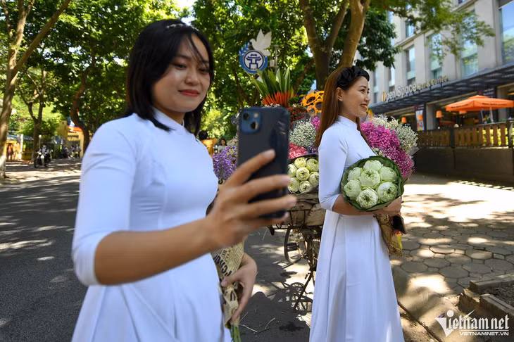 8h sáng, hai bạn trẻ Giang và Tuyết từ thị xã Sơn Tây lên Phan Đình Phùng (hơn 50km) để chụp ảnh hoa với áo dài. “Thời tiết đẹp như thế này mà ở nhà hơi phí, do đó chúng tôi quyết định nghỉ một buổi để đi chơi. Hoa năm nay rất đẹp, chúng tôi mua được 2 bó ưng ý”, Giang chia sẻ.
