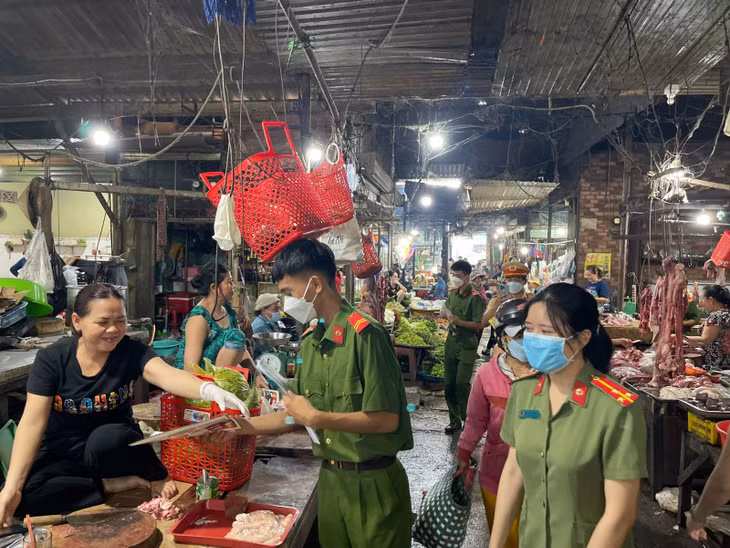 Cán bộ, chiến sĩ Công an phát tờ rơi tuyên truyền phòng, chống tội phạm tới bà con tiểu thương.