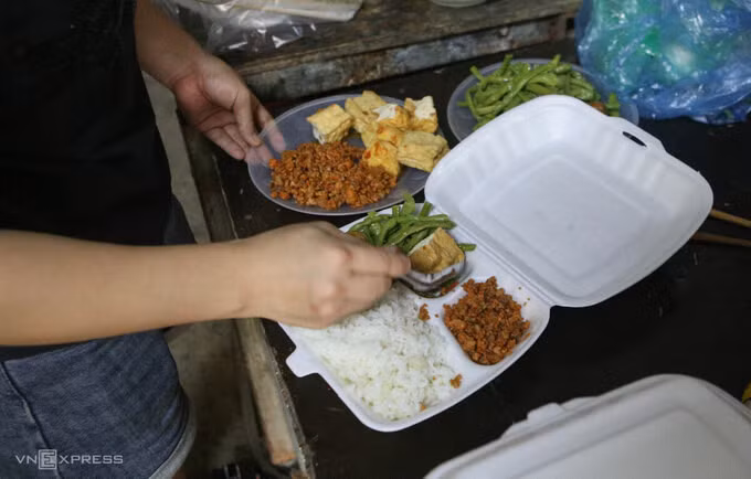 Một công nhân ở Phú La chia đồ ăn sau khi nhận được cơm từ bếp ăn của nhóm "Bình an trở lại", một trong hai bếp thuộc chương trình Triệu bữa cơm - Hà Nội nghĩa tình. Ảnh: Hồng Chiêu
