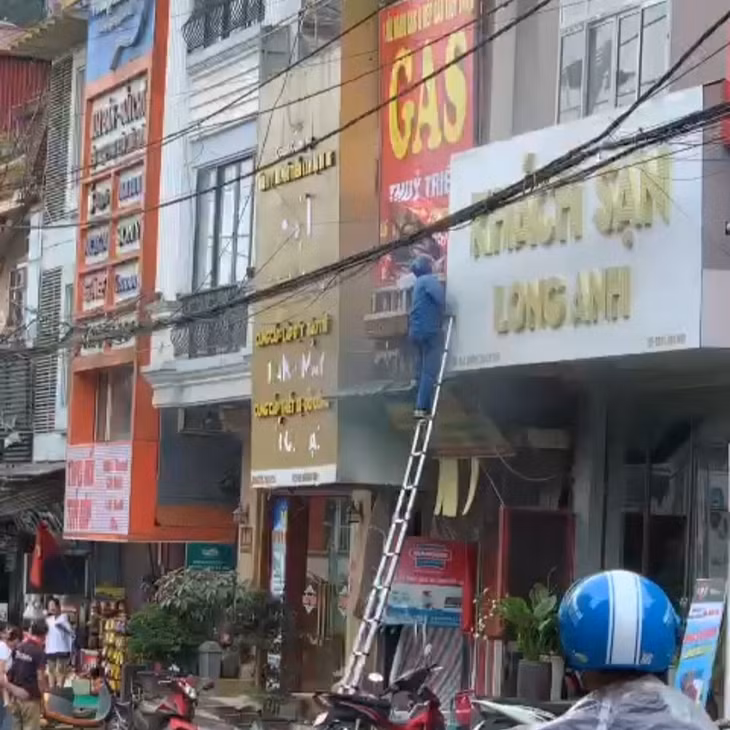 Nhân viên của VNPT Lào Cai trèo thang lên phá biển quảng cáo và cửa kính tạo lối thoát cho nạn nhân. Ảnh chụp màn hình.