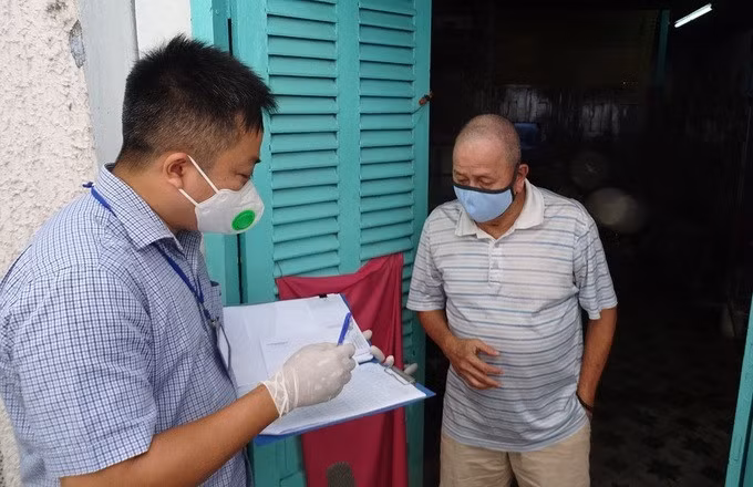 Ông Vương Chí Tài (phải), 72 tuổi, làm nghề bán vé số, ở phường Đa Kao, quận 1, nhận tiền hỗ trợ đợt một, trưa 12/7. Ảnh: Hà An