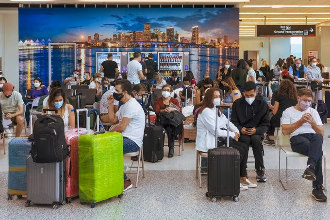 Hành khách đang ngồi đợi chuyến tại sân bay ở Miami hồi tháng 6. Ảnh: NYT