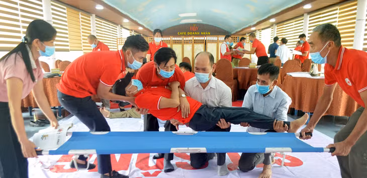 Các tình nguyên viên sơ cấp cứu ATGT đang thực hành thao tác kỹ thuật vận chuyển nạn nhân an toàn.