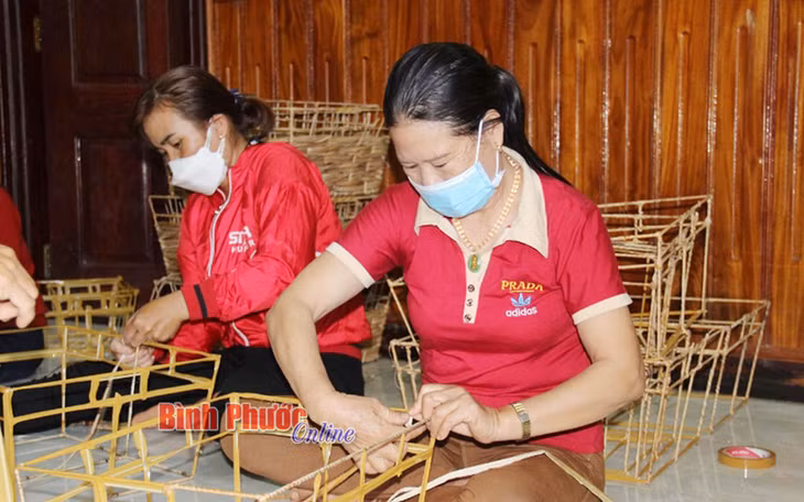 Các chị em trong Tổ nghề đan giỏ lục bình ấp 4, xã Hưng Phước thoăn thoắt đan các giỏ lục bình để kịp tiến độ bàn giao cho khách.