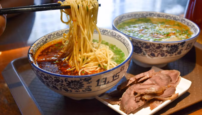 Mì bò Lan Châu, Trung Quốc Món ăn là sự kết hợp hoàn hảo giữa mì, nước lèo cay hấp dẫn cùng thịt bò mềm mại, được đánh giá là phù hợp ăn trong ngày trời lạnh. Một tô mì đạt chuẩn phải có đầy đủ 5 yếu tố: nước lèo phải trong, củ cải có màu trắng, hẹ màu xanh tươi, ớt đỏ chót và sợi mì vàng óng ả. Món ăn này được ưa chuộng tại Trung Quốc, và có nhiều điểm tương đồng với phở Việt Nam. Ảnh: East West Bank