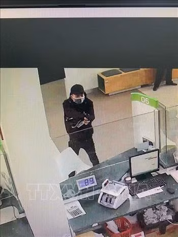 Đối tượng dùng súng uy hiếp nhân viên phòng giao dịch. Ảnh: TTXVN phát