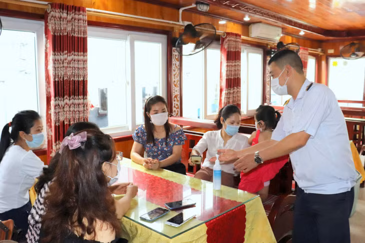 Nhân viên tàu du lịch trên Vịnh Hạ Long hướng dẫn du khách sát khuẩn, đảm bảo yêu cầu phòng, chống dịch Covid-19. Ảnh: Hoàng Quỳnh