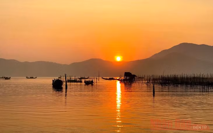 Mặt trời đỏ rực mang theo ánh sáng và hơi ấm lan tỏa khắp một vùng sông nước mênh mang, soi rõ những nhà chồ (nhà chòi) và “rừng” ô lồng nuôi cá, tôm… của ngư dân.