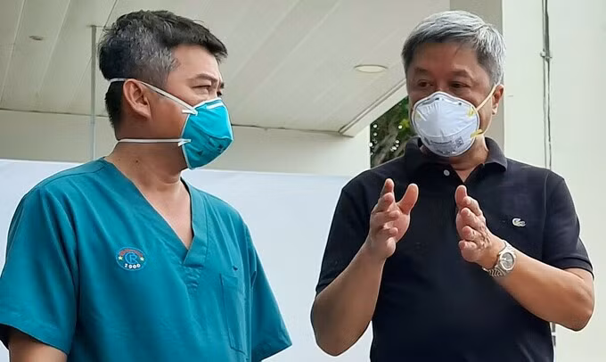 Thứ trưởng Y tế Nguyễn Trường Sơn (bên trái) trao đổi cùng bác sĩ Nguyễn Thành Linh, Phó giám đốc Bệnh viện Hồi sức Covid-19, chiều 26/7. Ảnh: Lê Phương.