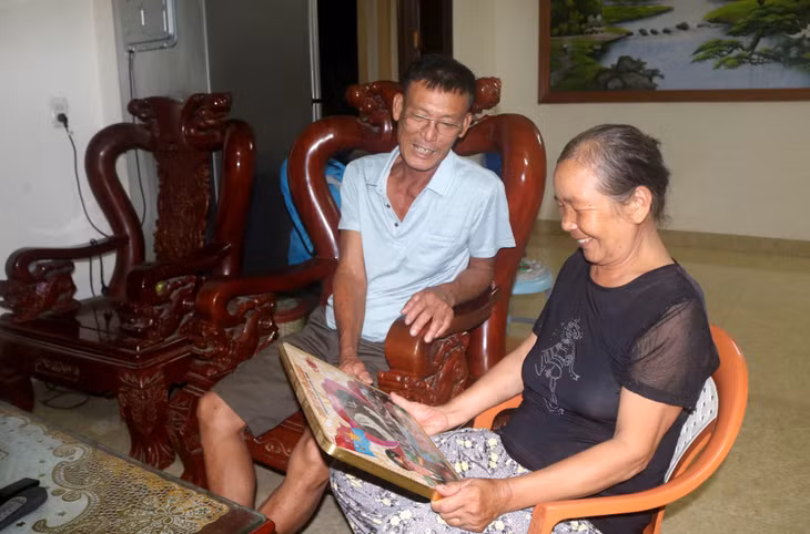 Bà Ngô Thị Nưu cùng chồng là thương binh Nguyễn Hữu Huấn xem lại ảnh kỷ niệm của ông Huấn.