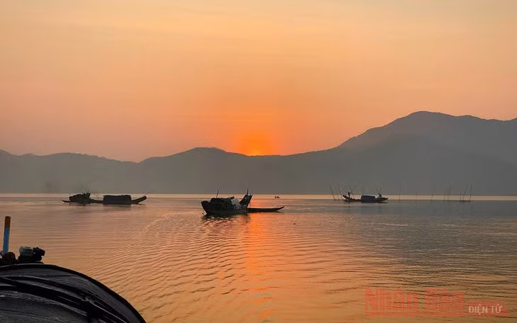 Trời sáng dần, toàn bộ không gian trời, mây, nước chuyển màu hồng cam, báo hiệu vầng thái dương sắp ló rạng.