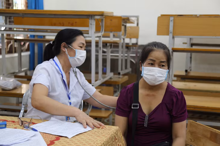 Các tiểu thương được đo thân nhiệt, khám sàng lọc trước khi tiêm.