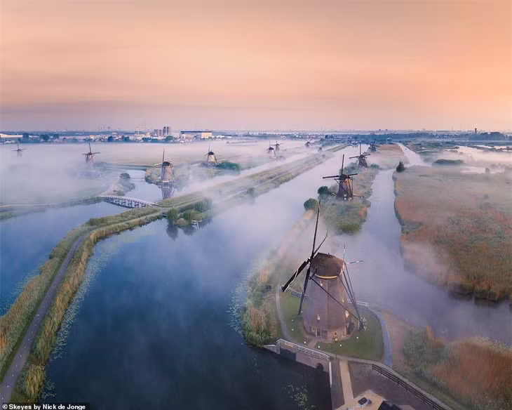 Sương mù bay trên những chiếc cối xay gió ở Kinderdijk. Trang web của ngôi làng giải thích rằng một nghìn năm trước, toàn bộ khu vực này “là một vũng than bùn lớn bị mắc kẹt giữa những con sông hung hãn”. Nhưng qua nhiều thế kỷ, cảnh ngập nước đã được cải thiện bằng cách sử dụng đê, cống, cối xay gió và trạm bơm