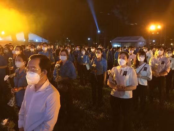 Người dân tham gia Lễ tưởng niệm chuẩn bị hoa, nến tại buổi lễ