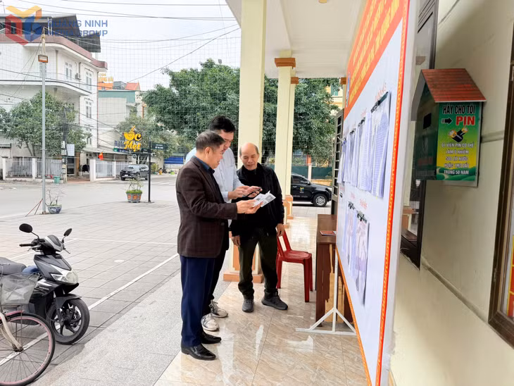 Người dân phường Cẩm Phả quét mã QR trên điện thoại để tìm hiểu thông tin bầu cử trong Cẩm nang phục vụ công tác tổ chức bầu cử do phường biên soạn.