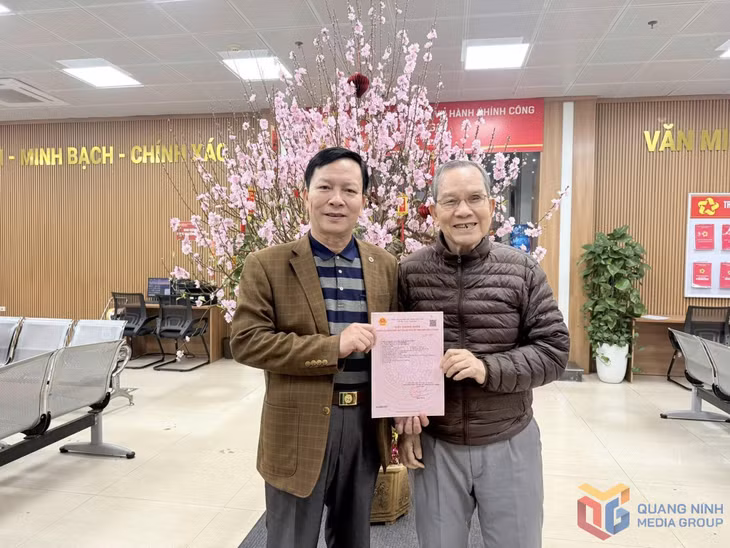Ông Trần Thông (bên phải) vui mừng khi được nhận “sổ hồng” của căn hộ tái định cư tại chung cư sau nhiều năm chờ đợi.