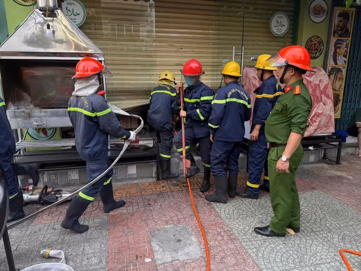 Lực lượng Cảnh sát Phòng cháy chữa cháy phá cửa cuốn và triển khai dập lửa. Ảnh: Phương Linh