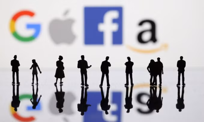 Mô hình người trước logo Google, Apple, Facebook và Amazon. Ảnh: Reuters