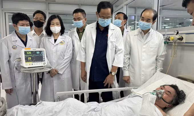 Phó Chủ tịch Quốc hội Trần Quang Phương (áo sơ mi xanh đậm), Bộ trưởng Y tế Đào Hồng Lan (thứ ba từ bên trái), Phó giám đốc Sở Y tế Hà Nội Nguyễn Đình Hưng (ngoài cùng bên phải) thăm nạn nhân vụ cháy Trung Kính điều trị tại Bệnh viện Giao thông Vận tải, sáng 24/5. Ảnh: Anh Phú
