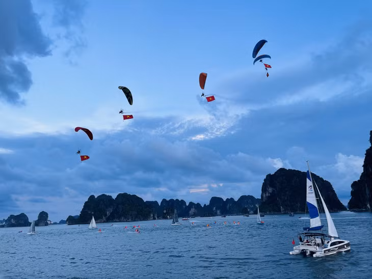 Đội thuyền buồm và moto nước mang theo cờ Tổ quốc trình diễn theo đội hình.