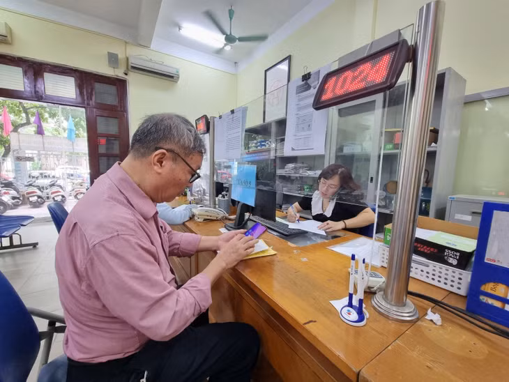 Làm thủ tục nhận lương hưu qua tài khoản ngân hàng. Ảnh: XC