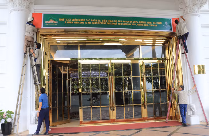 Nhân viên Khách sạn Royal Hạ Long treo băng rôn quảng bá về cuộc thi ABU Robocon 2024.