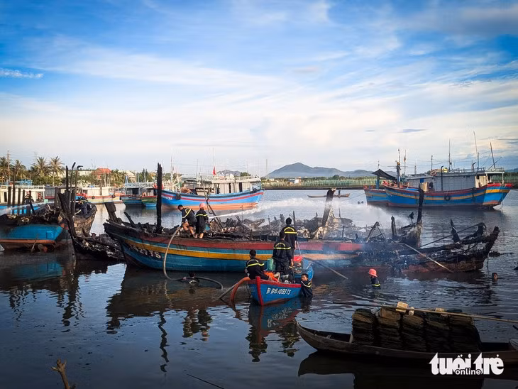Cảnh sát phòng cháy chữa cháy bơm nước làm mát những thân tàu bị cháy sau khi khống chế ngọn lửa - Ảnh: TẤN LỰC