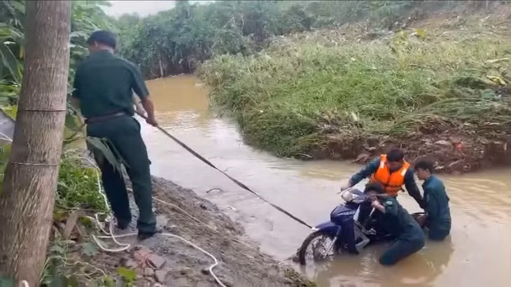 Lực lượng chức năng trục vớt xe máy bị nước cuốn trôi.