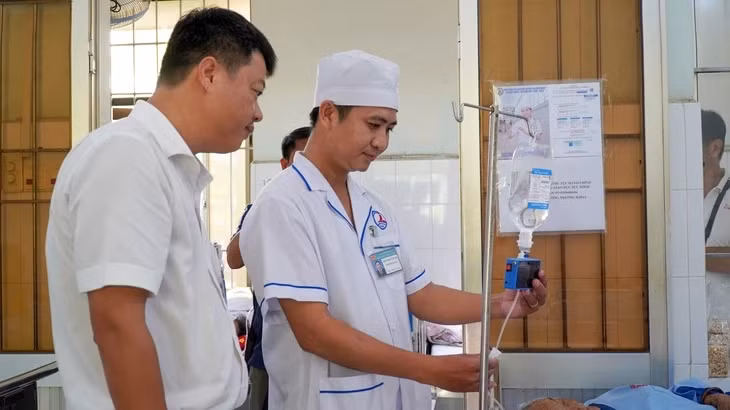Thạc sĩ Dưỡng (bên trái) hướng dẫn cho nhân viên y tế sử dụng máy - Ảnh: THANH HUYỀN