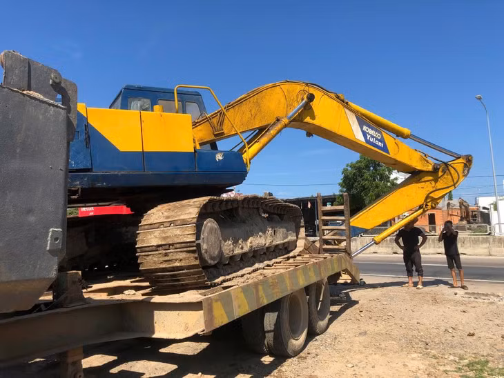 Xe múc được chở trên móc kéo ở sau xe ben. Ảnh: Duy Tuấn