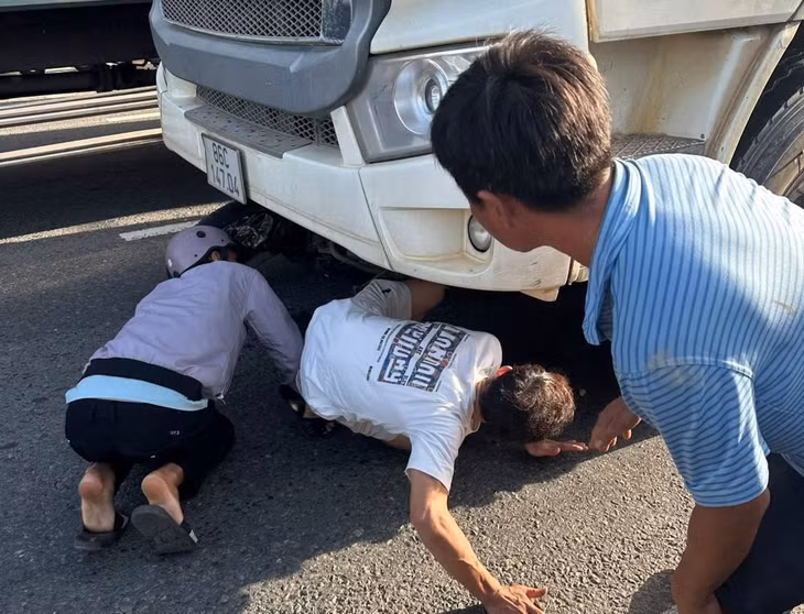 Người dân hợp sức giải cứu nạn nhân bị kẹt dưới gầm xe. Ảnh: Duy Tuấn