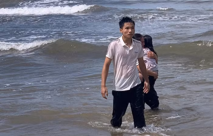 Em Lê Đức Trung cùng cháu bé vào bờ an toàn. Ảnh: Hàn Nguyên