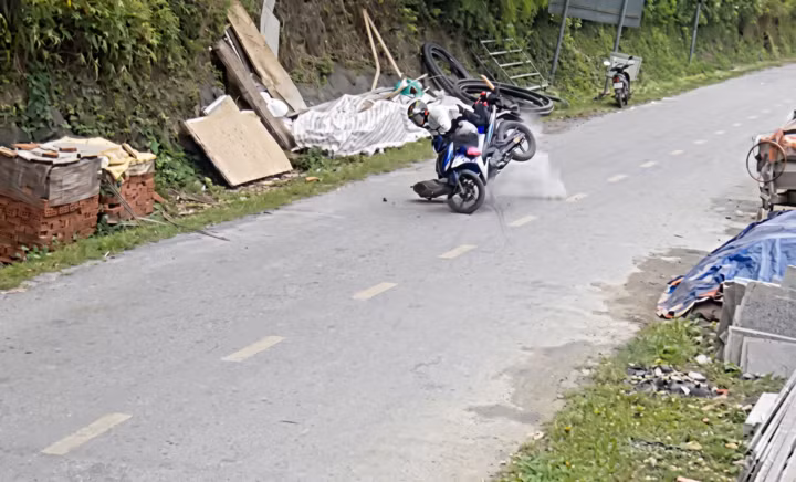 Đá lở bất ngờ từ vách núi, hất văng người đi xe máy xuống đường. (Ảnh cắt từ clip).