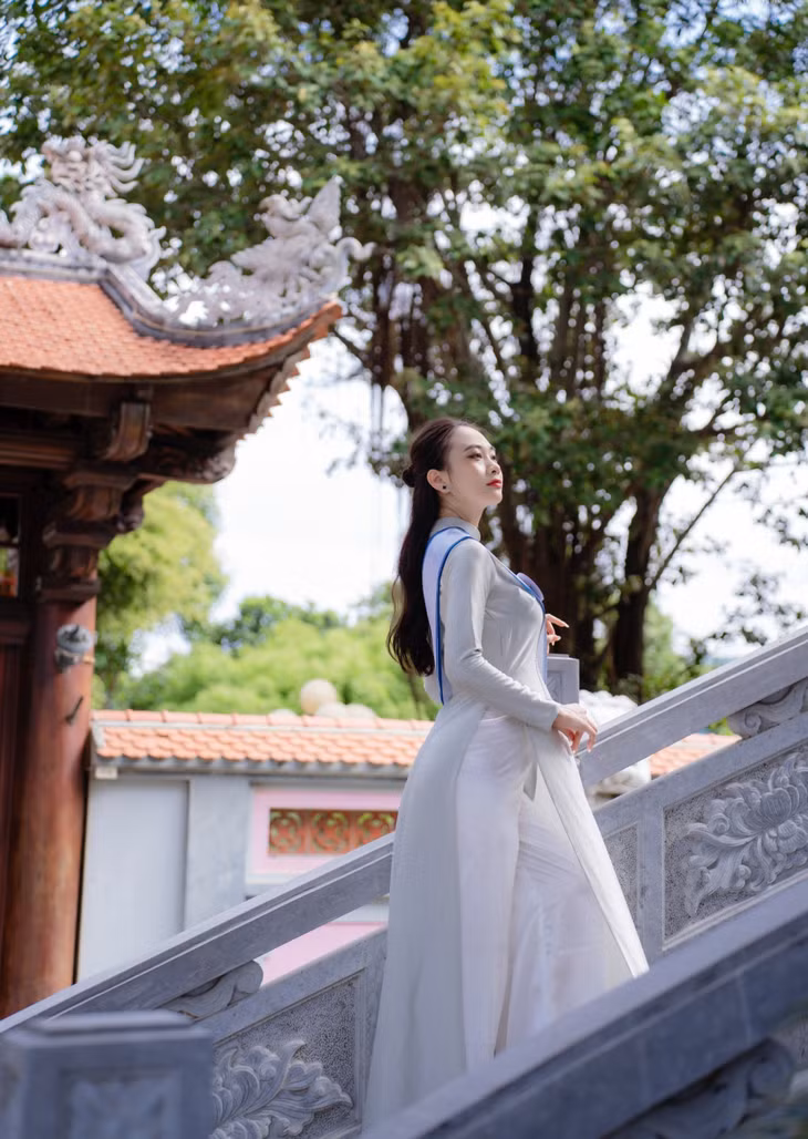 Các thí sinh duyên dáng bước đi trên bậc thang đá hoa cương, thấp thoáng phía sau là mái ngói âm dương cong vút của Đền Vũng Đục.