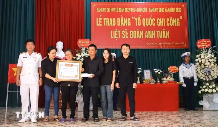 Đại diện Chỉ huy Lữ đoàn 682 (ngoài cùng bên trái) trao Bằng 'Tổ quốc ghi công' cho gia đình Liệt sỹ Đoàn Anh Tuấn. (Ảnh: TTXVN phát)