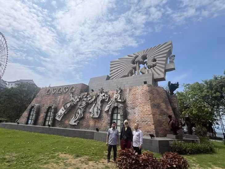 Nhà điêu khắc Phạm Văn Hạng (giữa) và các cộng sự dưới chân tượng đài.