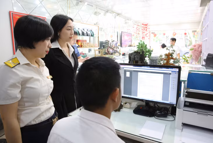Cán bộ Chi cục Thuế Hạ Long kiểm tra việc xuất hóa đơn điện tử trong giao dịch mua bán vàng tại một cửa hàng vàng trên địa bàn TP Hạ Long.
