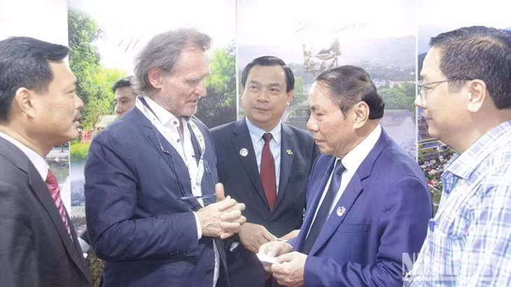 Một vị khách quốc tế trao đổi với Bộ trưởng Nguyễn Văn Hùng tại Gian hàng Du lịch Việt Nam. (Ảnh: Hải Tiến)
