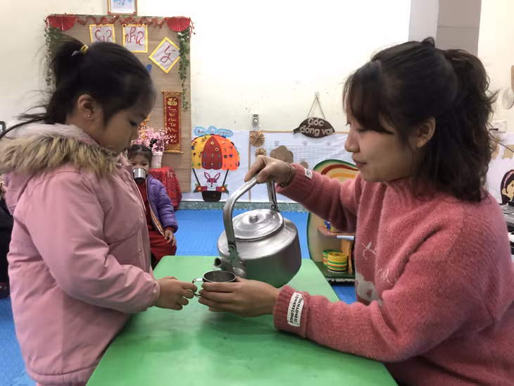 Giáo viên Trường Mầm non Vũ Oai (xã Vũ Oai, TP Hạ Long) cho trẻ uống nước ấm khi đến trường, ngày 23/1. Ảnh: Thu Phương