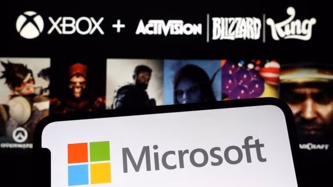 Logo Microsoft trên smartphone, phía sau là logo và hình ảnh trò chơi của Activision Blizzard. Ảnh: Reuters