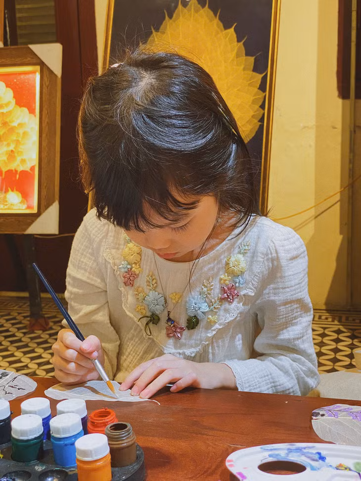 Một em nhỏ chăm chú vẽ tranh lá bồ đề.