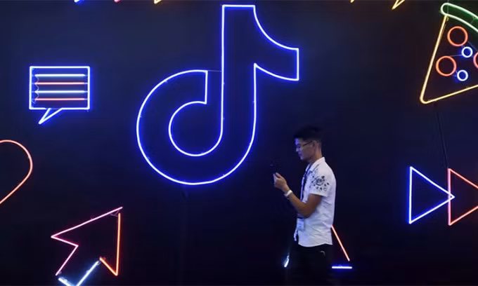 Một người dùng tại Trung Quốc đi qua biển hiệu TikTok. Ảnh: Reuters