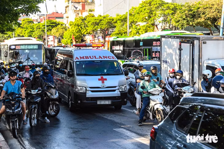 Người Hà Nội nhường đường cho chiếc xe cấp cứu tại một nút giao dù đang trong nhịp đèn đỏ - Ảnh: HỒNG QUANG